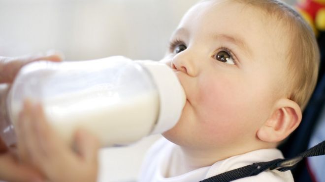 Ребенок пьет. Девятимесячный мальчик пьет бутылку молока. кормить ребенка