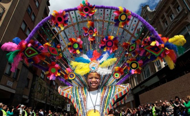 Исполнитель танцует на уличном параде на ежегодном карнавале в Ноттинг Хилле