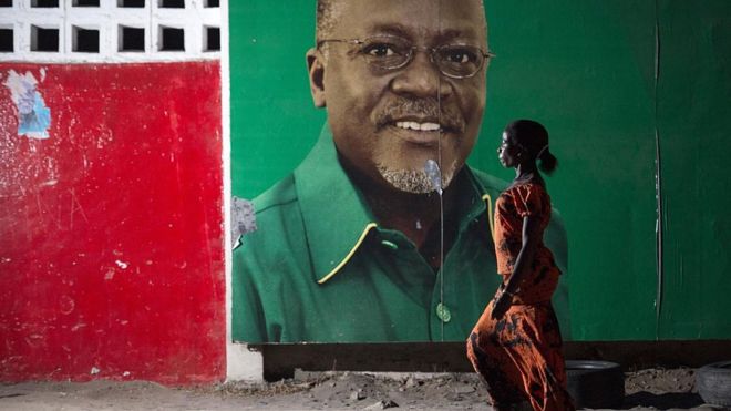 Женщина проходит мимо избирательного щита после того, как 29 октября 2015 года Национальная избирательная комиссия в Дар-эс-Саламе избрала кандидата от правящей партии Чама Ча Мапиндузи (СКК) Джона Магуфули (на фото на доске объявлений).