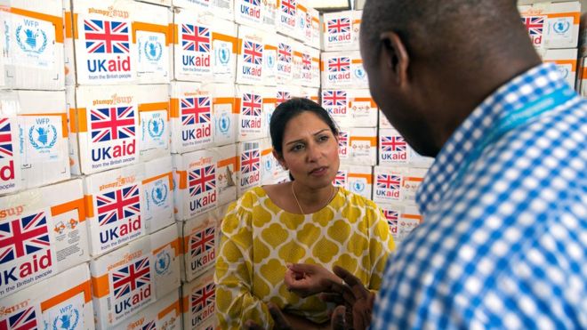 Britain"s International Development Secretary Priti Patel speaks with a humanitarian aid agency worker in front of boxes of food aid at Mogadishu airport, Somalia June 17, 2017.