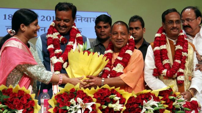 Старший лидер Индийской партии Бхаратия Джаната (BJP) М. Венкайя Найду (справа) Уттар Прадеш Лидеры BJP Прасад Маурья (2л) и Динеш Шарма (2р) смотрят, как Йоги Адитьянатх (C) преподносят цветочный букет во время церемонии в Лакхнау 18 марта 2017 года, после того, как он был избран новым главным министром штата Индийский штат Уттар-Прадеш