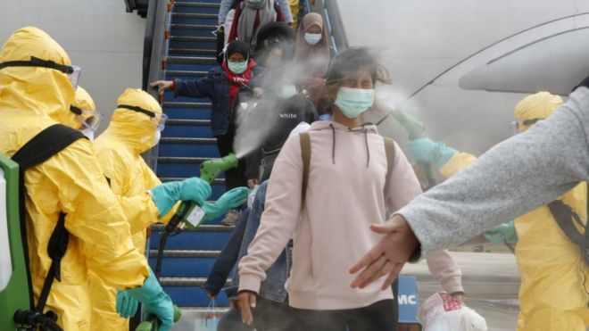 Медицинские работники распыляют антисептик на граждан Индонезии после того, как они прибыли из Ухани