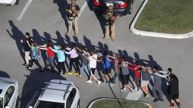 Люди вывезены из средней школы имени Марджори Стоунмана Дугласа после стрельбы в школе, которая, как сообщается, убила и ранила несколько человек 14 февраля 2018 года в Паркленде, штат Флорида.