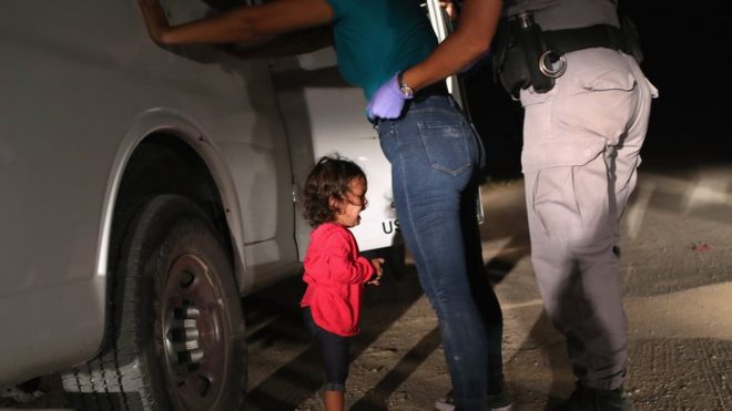 A two-year-old Honduran asylum seeker cries as her mother is searched and detained near the US-Mexico border on 12 June 2018 in McAllen, Texas.