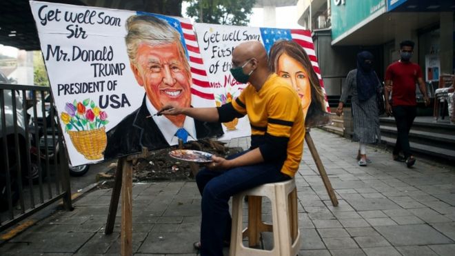 Мужчина рисует фреску с изображением президента США Дональда Трампа и первой леди Мелании после того, как они дали положительный результат на коронавирус на улице в Мумбаи, Индия