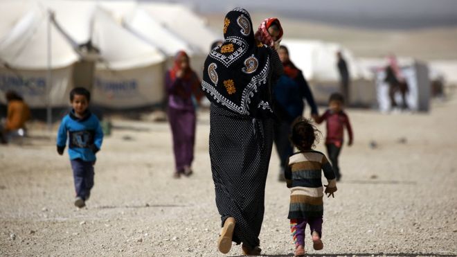 An Iraqi refugee carries her child as she walks around in a camp in al-Hawl, in Syria's Hassakeh province, on 13 March 2017