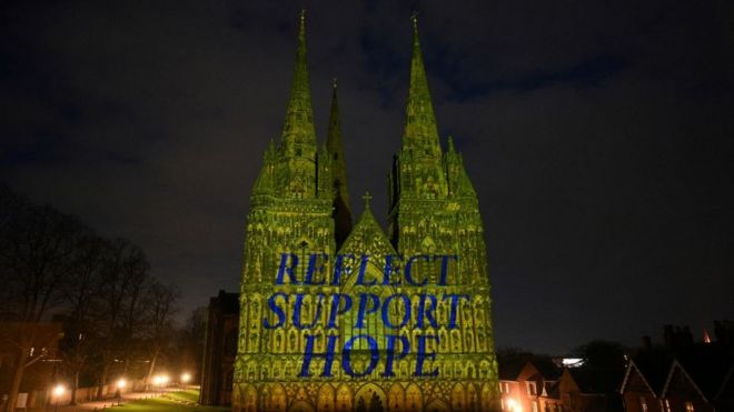 Lichfield Cathedral is illuminated in yellow light, with the words 'Reflect', 'Support', and 'Hope'.