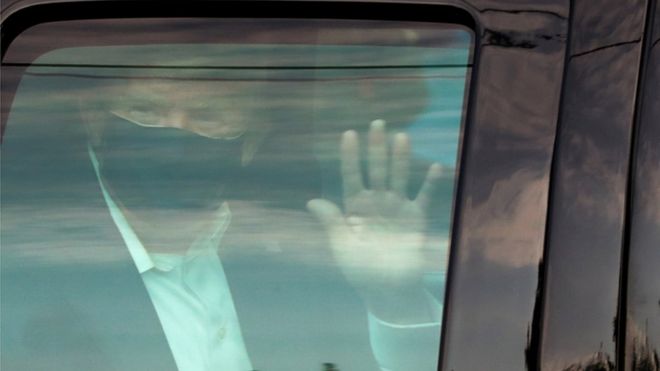 Президент Дональд Трамп машет сторонникам, когда он ненадолго проезжает в президентском кортеже перед Национальным военно-медицинским центром Уолтера Рида