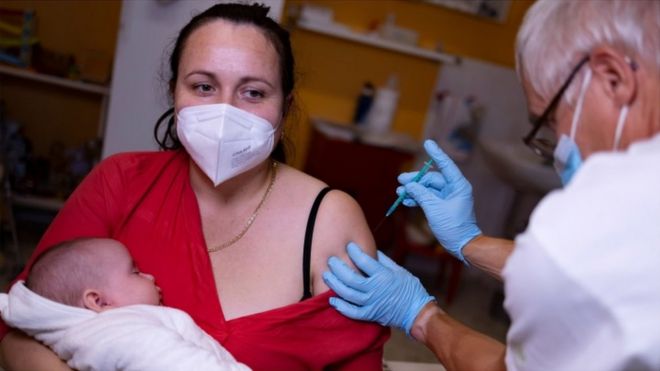 A doctor administers a coronavirus disease (COVID-19) vaccine to a woman holding a baby, in his doctor"s office in Berlin, Germany, November 2, 2021