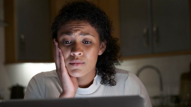 Женщина просматривает оскорбительные сообщения на своем компьютере