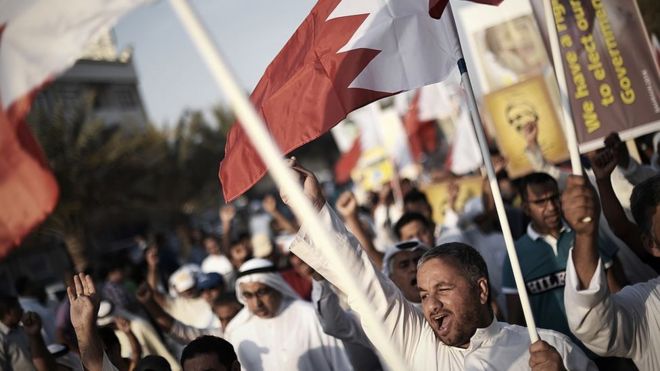 Фотография из архива бахрейнцев, выкрикивающая лозунги и машущая своим национальным флагом во время антиправительственной акции протеста в Джаннусане, к западу от Манамы, 9 мая 2014 года