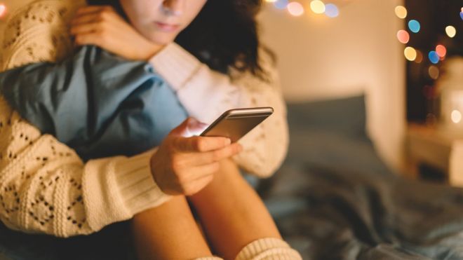 Девушка в постели с помощью социальных сетей на своем телефоне