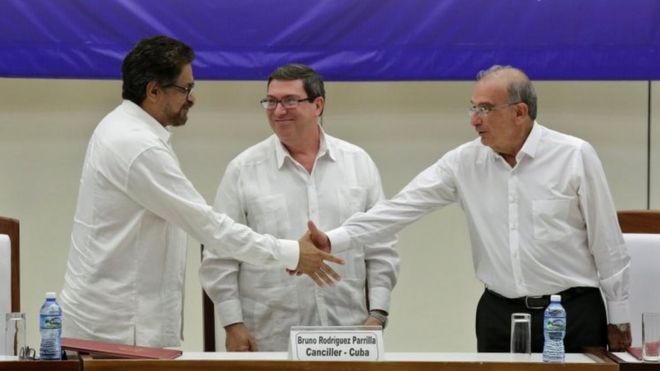 Ведущий переговорщик Колумбии по Фарку Иван Маркес (слева) и ведущий правительственный переговорщик Колумбии Умберто де ла Калле (справа) обмениваются рукопожатиями, в то время как министр иностранных дел Кубы Бруно Родригес смотрит на это после подписания окончательного мирного соглашения в Гаване, 24 августа 2016 г.