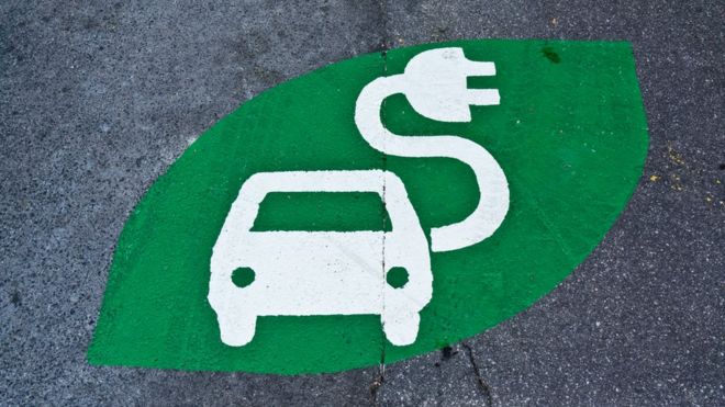 Зеленый знак зарядки электромобилей, нарисованный на дороге
