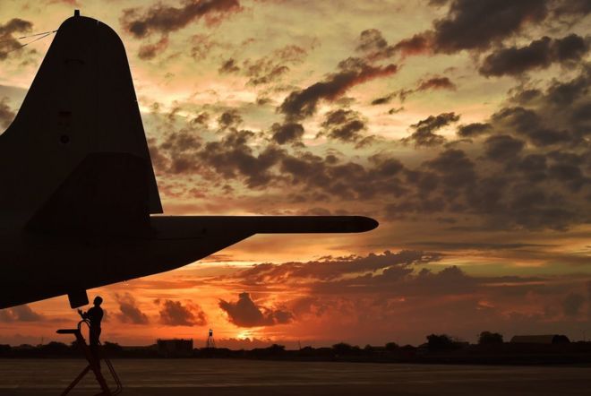 Летчик проводит технические проверки самолета-разведчика на закате солнца в Джибути
