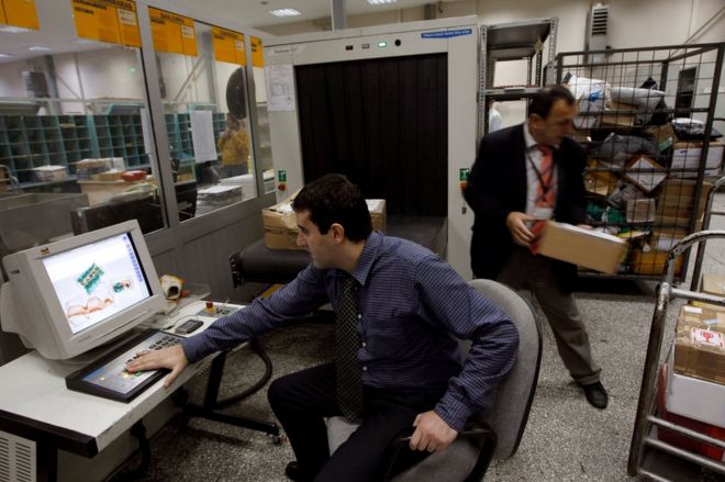 Сотрудник службы безопасности смотрит на экран, на котором отображаются посылки, просканированные рентгеновским излучением, в почтовом логистическом центре Почты Турции (PTT) в международном аэропорту Ататюрк в Стамбуле, Турция, 6 ноября 2010 года