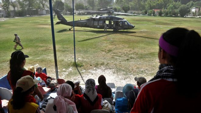Члены женской сборной Афганистана по футболу отдыхают от тренировок, поскольку американский вертолет Black Hawk приземляется на поле в военном клубе в Кабуле 20 июня 2010 года.