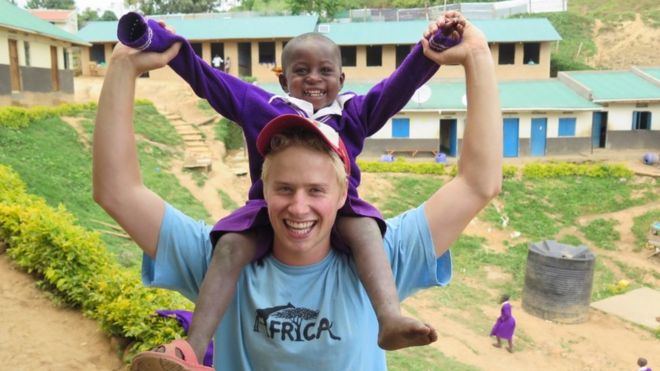 Эдвард Сеньор во время учебного года в Африке. У него на плечах молодой африканский мальчик. Оба улыбаются.