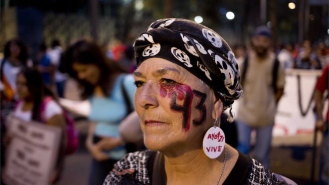 Женщина с номером 43 на лице, ссылаясь на 43 пропавших студентов из сельской школы учителей, участвует в марше в Мехико, четверг, ноябрь.26, 2015