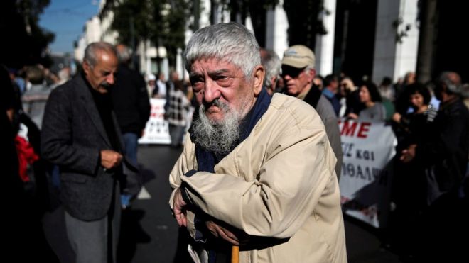 Греческий пенсионер опирается на пастушьего мошенника во время демонстрации против запланированных сокращений пенсий в Афинах, Греция, 3 ноября 2016 года