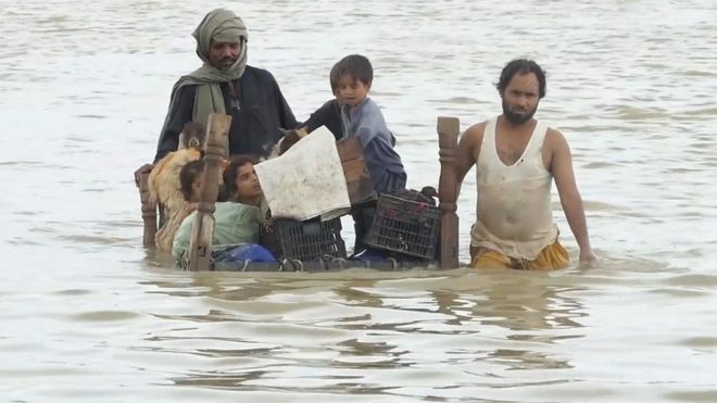 A family wade through flood waters in Pakistan