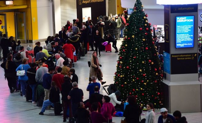 A queue of passengers next to a Christmas tree