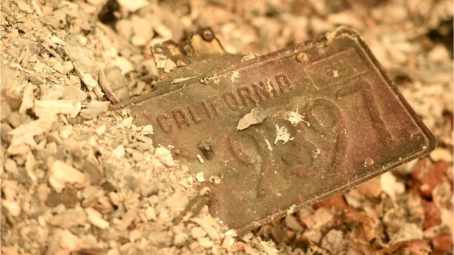 Калифорнийский номерной знак виден частично похороненным в куче пепла в сгоревшей резиденции после того, как пожар Кэмпа разорвал регион в Раю, штат Калифорния, 12 ноября 2018 года
