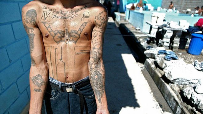 Член MS-13 показывает свои татуировки в тюрьме