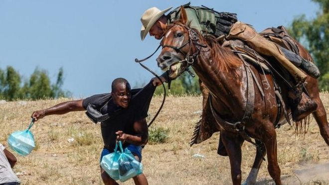 Un agente fronterizo a caballo agarra a un migrante en Texas.