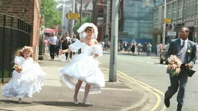 Жених и невеста и их подружка бежит по центру города