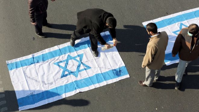 Iranian protesters pour kerosene on an Israeli flag during the funeral procession of Brigadier General Mohammad Ali Allahdadi in Tehran on January 21, 2015.