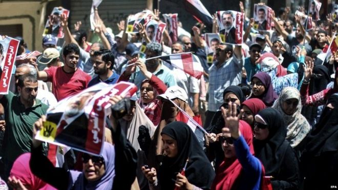 Египтяне совершают четырехпалый салют, связанный с резней в правительстве мирных демонстрантов в поддержку запрещенного ныне Братьев-мусульман 14 августа 2015 г.