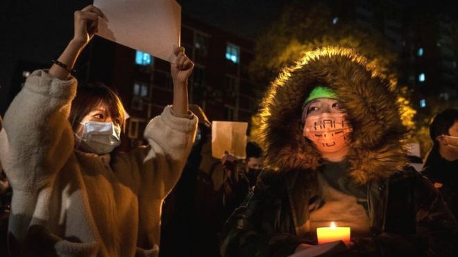 2022年11月27日，在北京的抗议者手持蜡烛作为抗议象征的白纸。