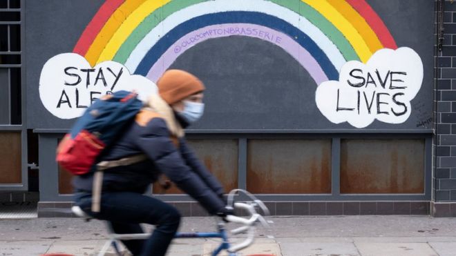 A person cycles past a Covid mural in winter last year
