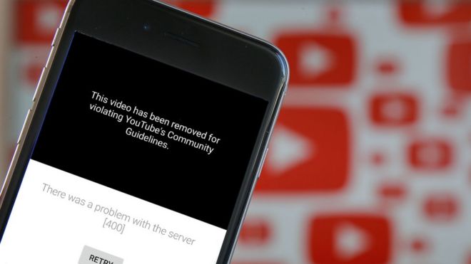 A photo illustration shows the YouTube app on a mobile phone with the message that the video has been taken down