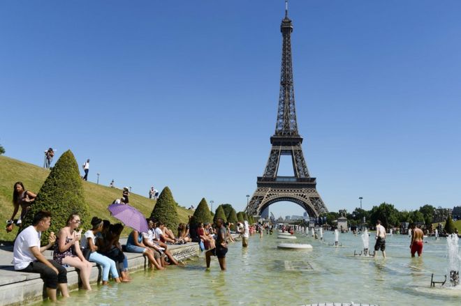 Люди освежаются в воде фонтанов Трокадеро перед Эйфелевой башней в Париже, 19 июля