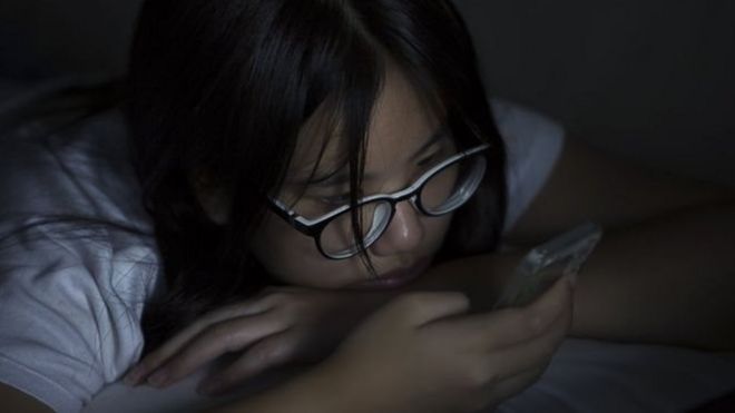 Akşam yatakta cep telefonunu kontrol eden bir genç kız