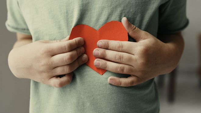 Un niño sostiene un corazón de papel