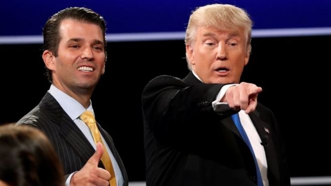 Дональд Трамп младший (слева) показывает большой палец рядом со своим отцом на дебатах в Хемпстеде, Нью-Йорк.