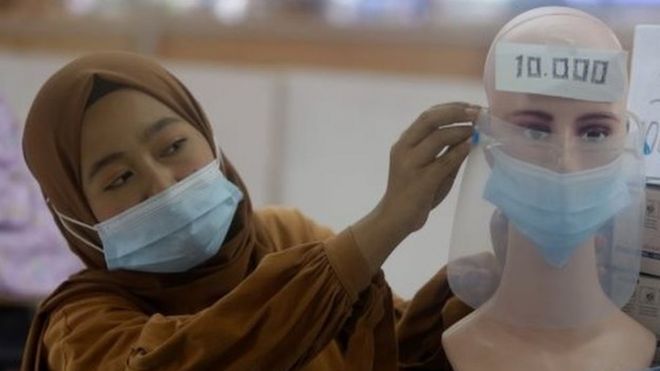 A vendor arranges a mask attached to a mannequin at a shopping mall in Jakarta, Indonesia, 04 January 2021.