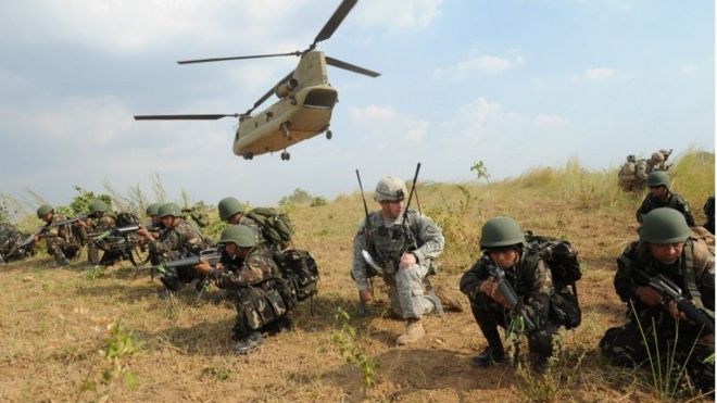 Philippine soldiers and a US Army soldier take their positions after disembarking from a C-47 Chinook helicopter during an exercise at a military training camp in the Philippines (April 2015)