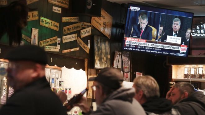 Люди наблюдают за расследованием дела об импичменте в баре в Чикаго, штат Иллинойс