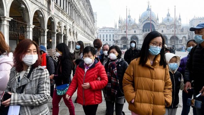 Tourists wearing protective facemasks visit the Piazza San Marco, in Venice, on February 24, 2020
