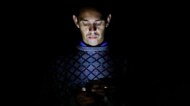 Hombre iluminado por la luz del teléfono.