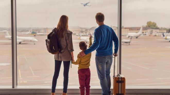 семья в аэропорту наблюдает за взлетом самолета