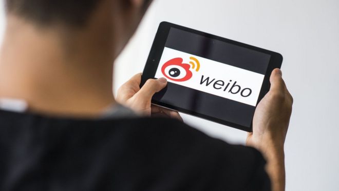 Мужчина использует социальную сеть Sino Weibo на мобильном устройстве