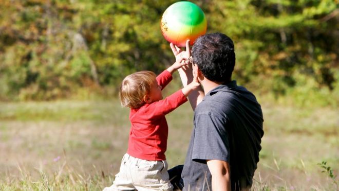 Человек играет с мячом с маленьким мальчиком