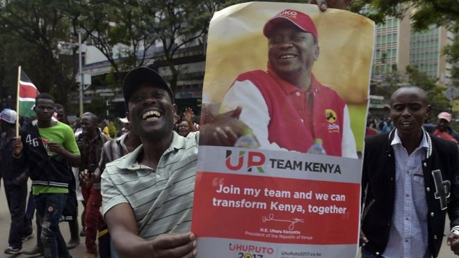 Сторонники президента Ухуру Кеньятты держат плакат с изображением Кеньятты во время празднования 20 ноября 2017 года в Найроби