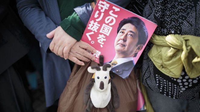 Рука, держащая рекламную листовку Синдзо Абэ