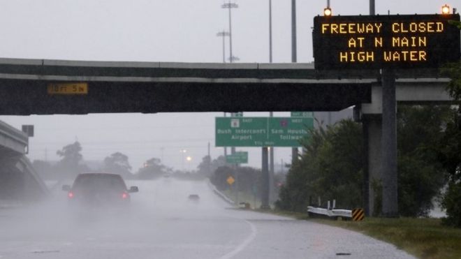 A pick-up truck passes a warning sign on southbound Interstate 45 north of Houston, TX, as heavy rains from the remnants of Hurricane Harvey continue to flood many areas of the city (27 August 2017)